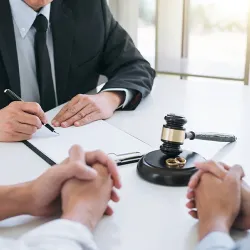 A divorced couple sitting in front of a judge with paperwork